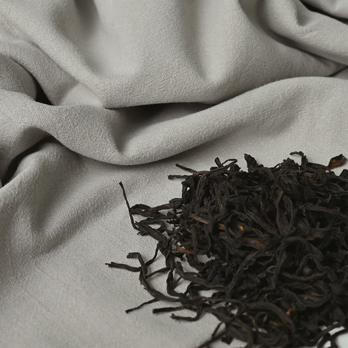 Tea leaves arranged on a naturally colored textile.